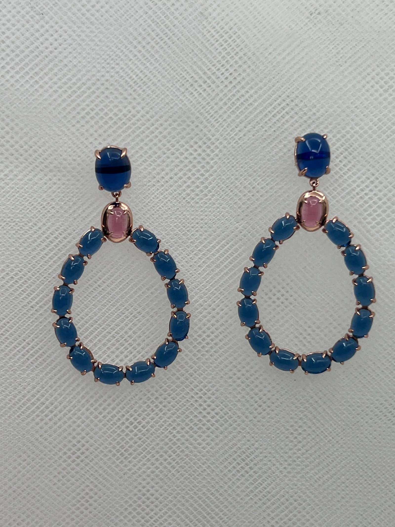 Pendientes largos de plata chapada en oro rosa ovalos con piedras cabujon de color azul y rosa.