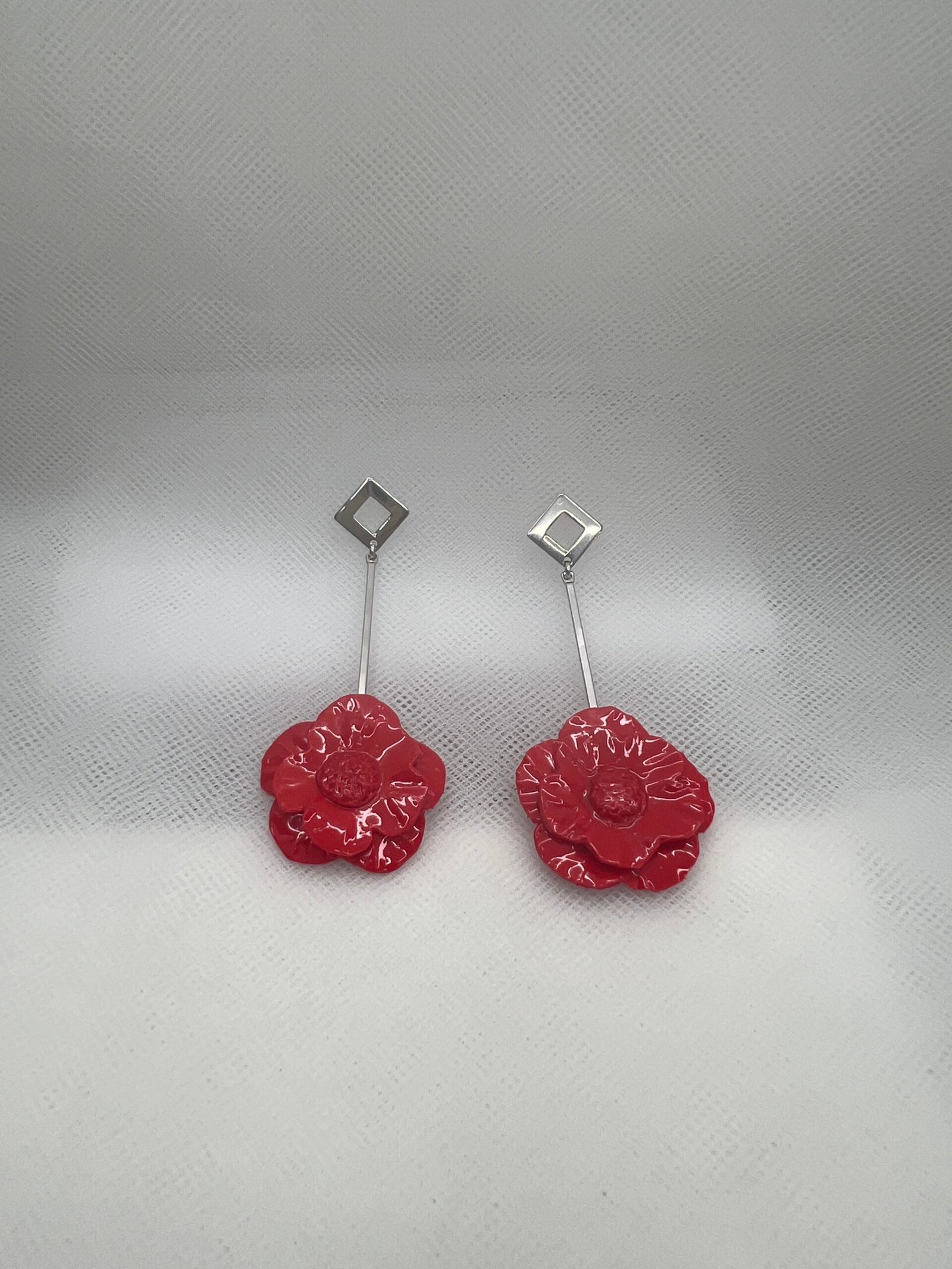 Pendientes largos de acero con flores de porcelana rojas.
