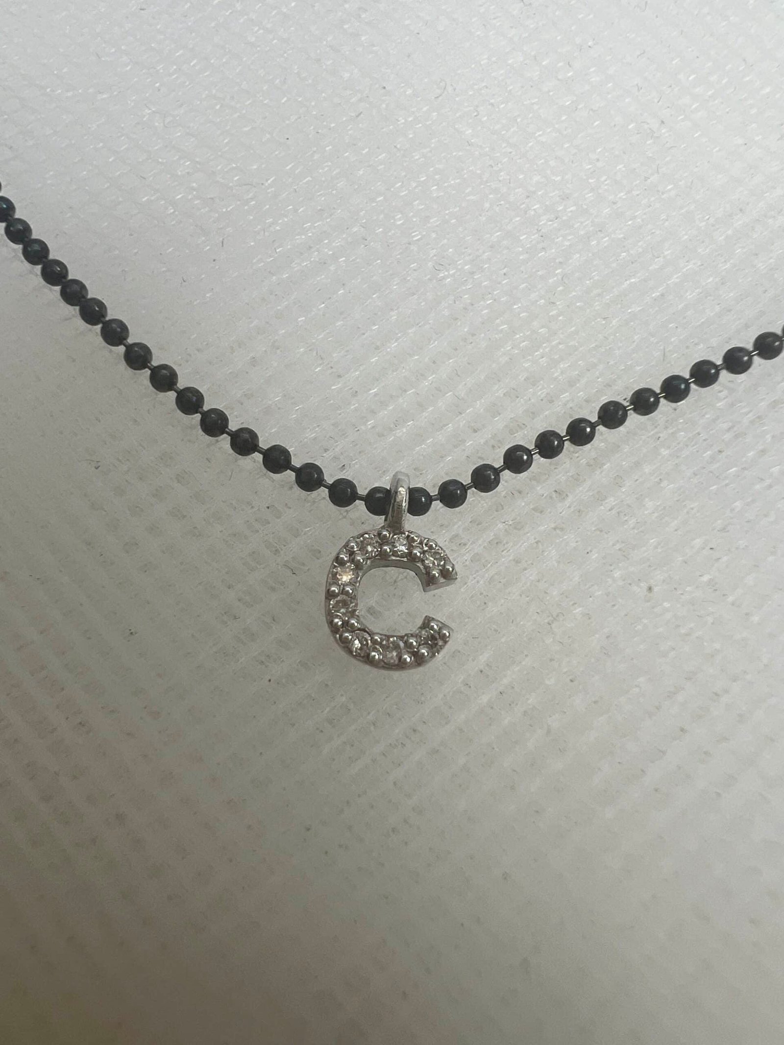 Collar de plata negra con inical de oro blanco con brillantes.