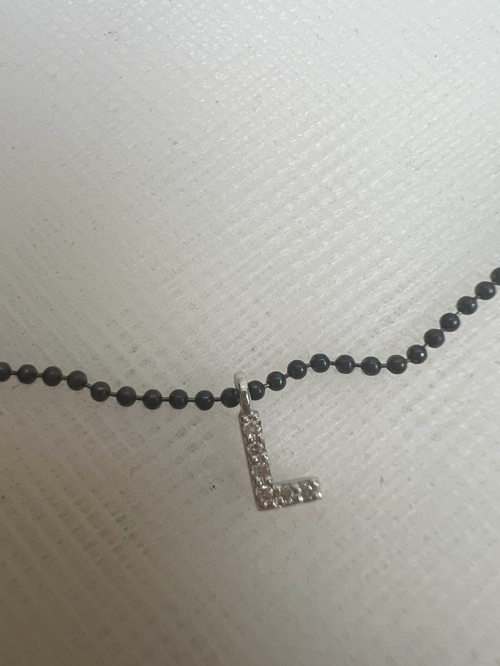 Collar de plata negra con inicial de oro blanco con brillantes.