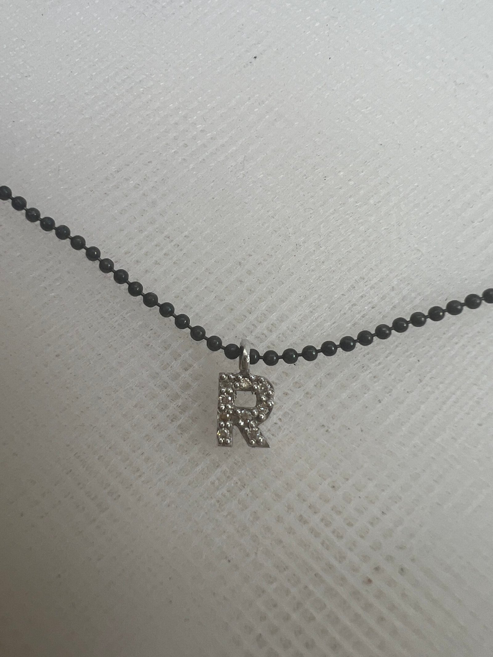 Collar de plata negra con inicial de oro blanco y brillantes.