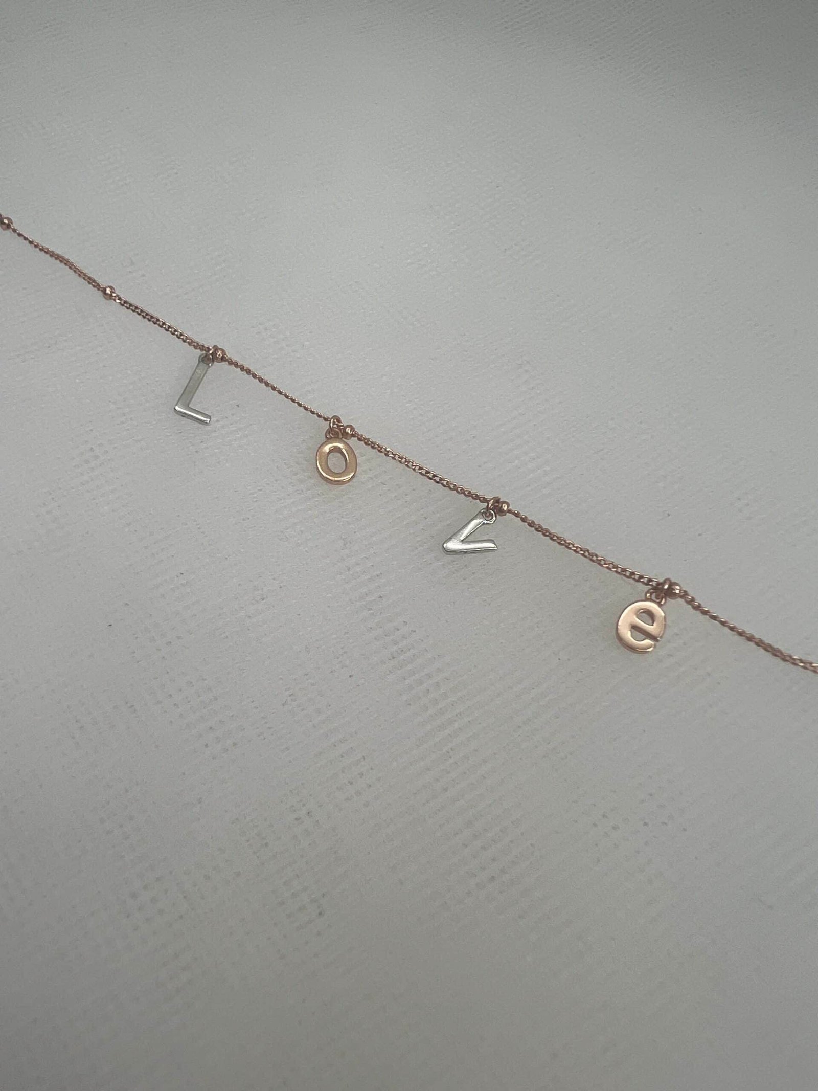 Pulsera de plata chapada en oro rosa con letras.