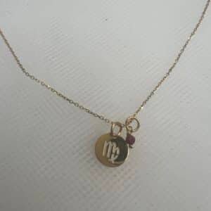 Cadena de oro amarillo con colgante de horoscopo y rubi.