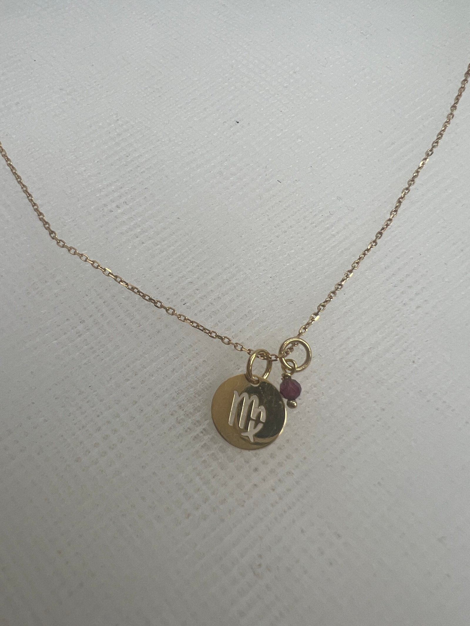 Cadena de oro amarillo con colgante de horoscopo y rubi.