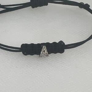 Pulsera de macrame de color negro con inicial de oro blanco y brillantes.