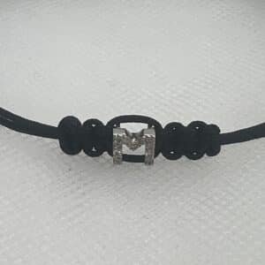 Pulsera de macrame de color negro con inicial en oro blanco y brillantes.