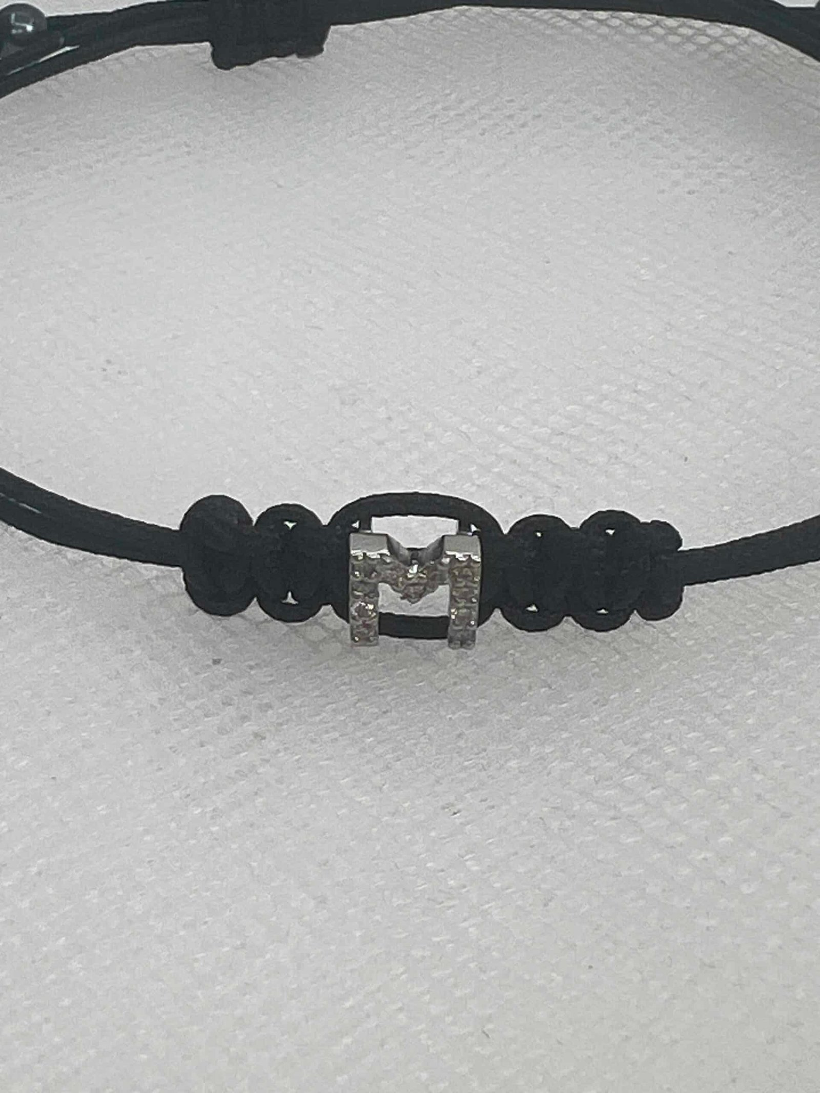 Pulsera de macrame de color negro con inicial en oro blanco y brillantes.