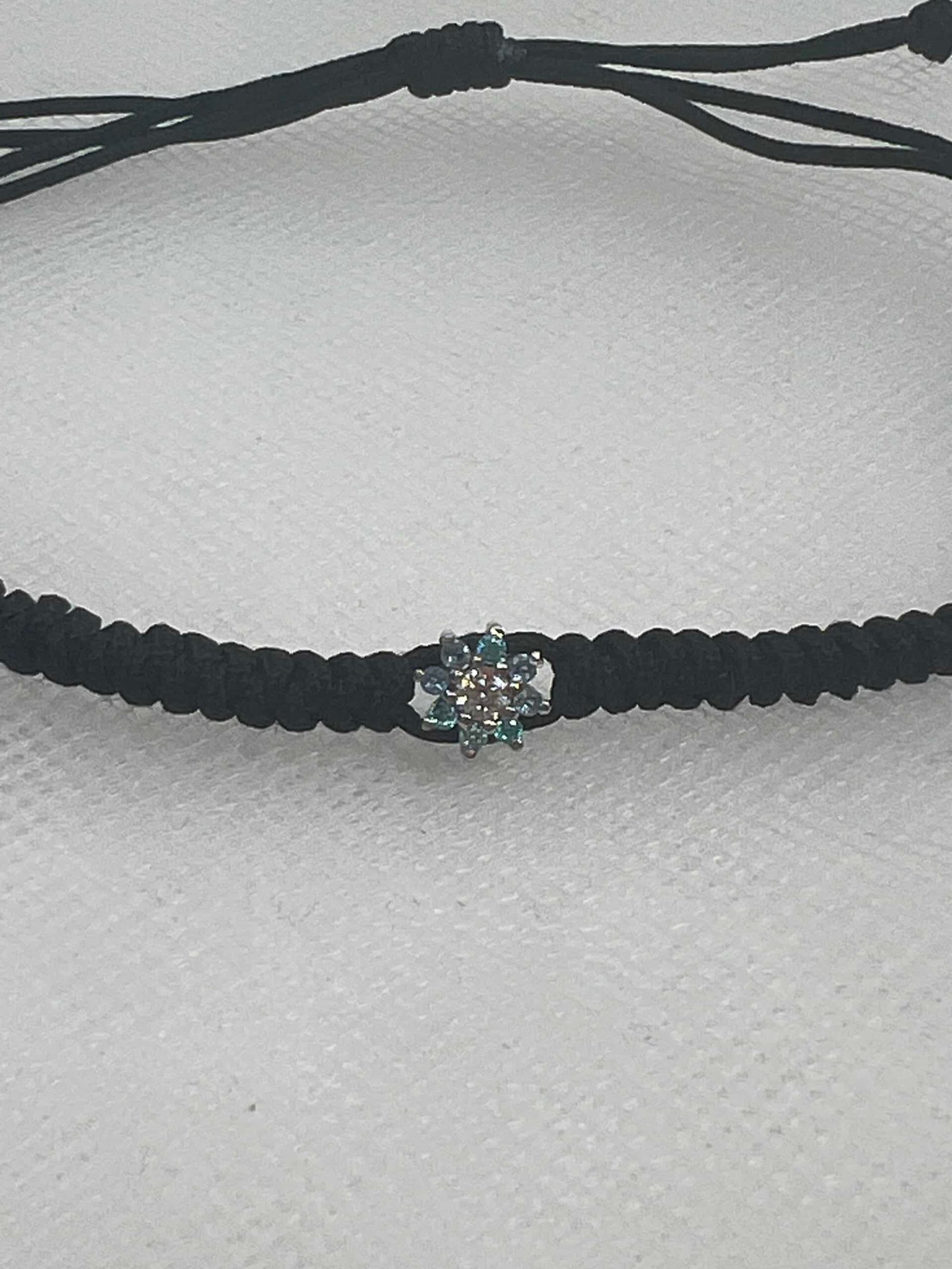 Pulsera de macrame de color negro con roseton de oro blanco con aguamarinas y brillante.