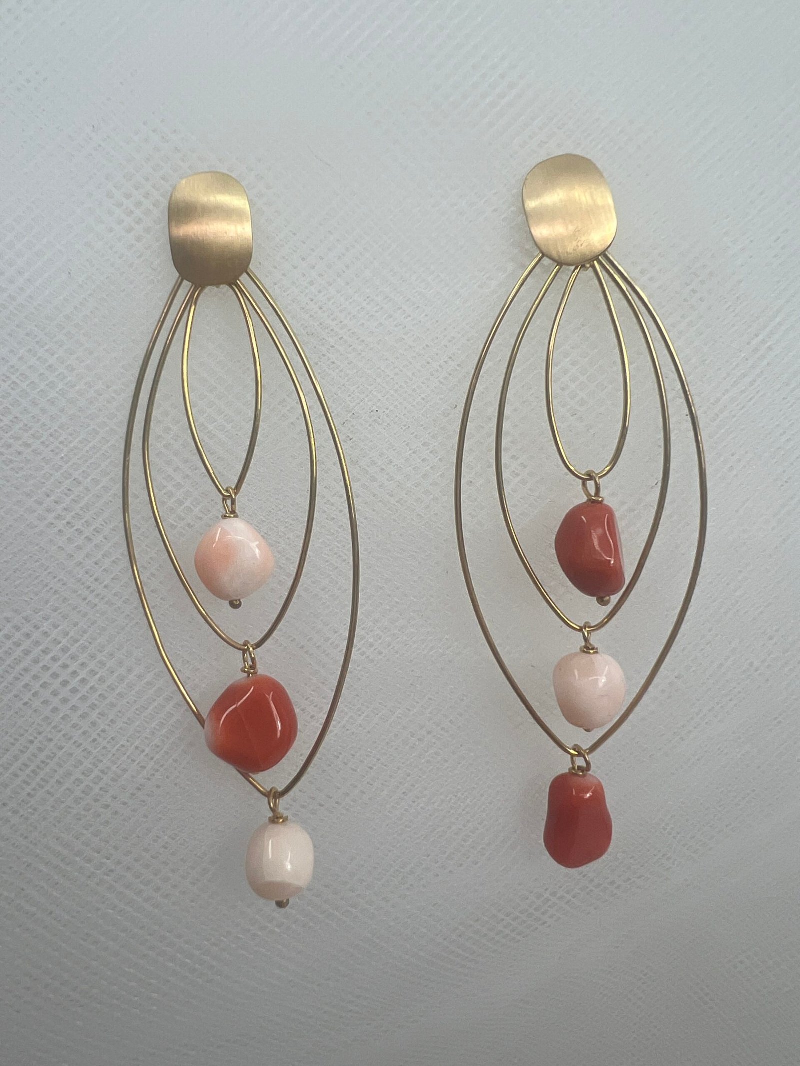 Pendientes de oro amarillo de aros entrelazados con corales naturales rojos y rosas.
