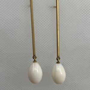 Pendientes largos de oro amarillo matizado y gotas de coral natural blanco.