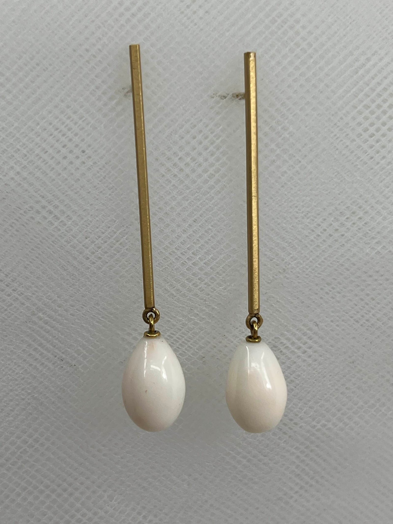 Pendientes largos de oro amarillo matizado y gotas de coral natural blanco.