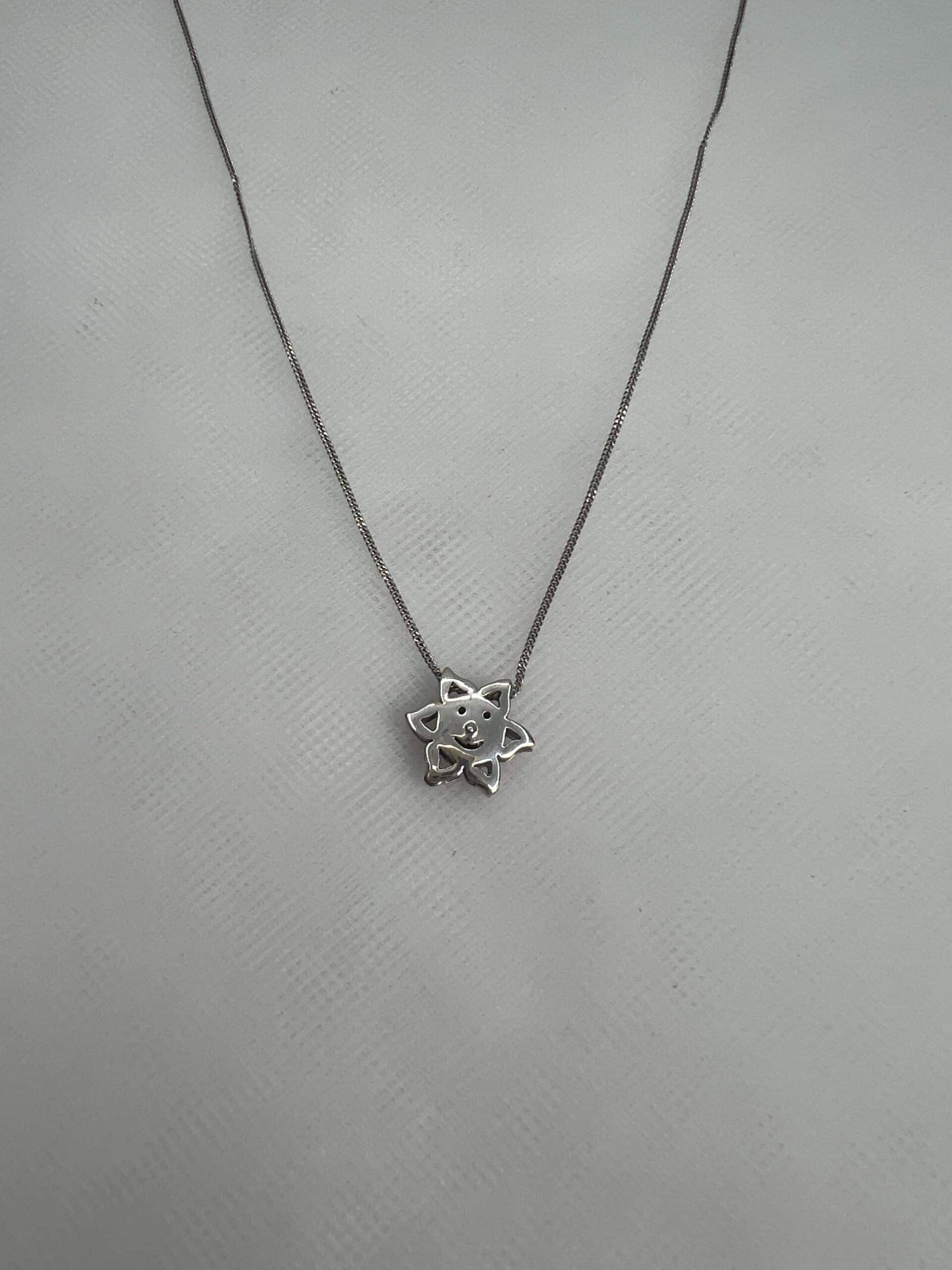 Cadena y colgante de oro blanco con forma de sol.