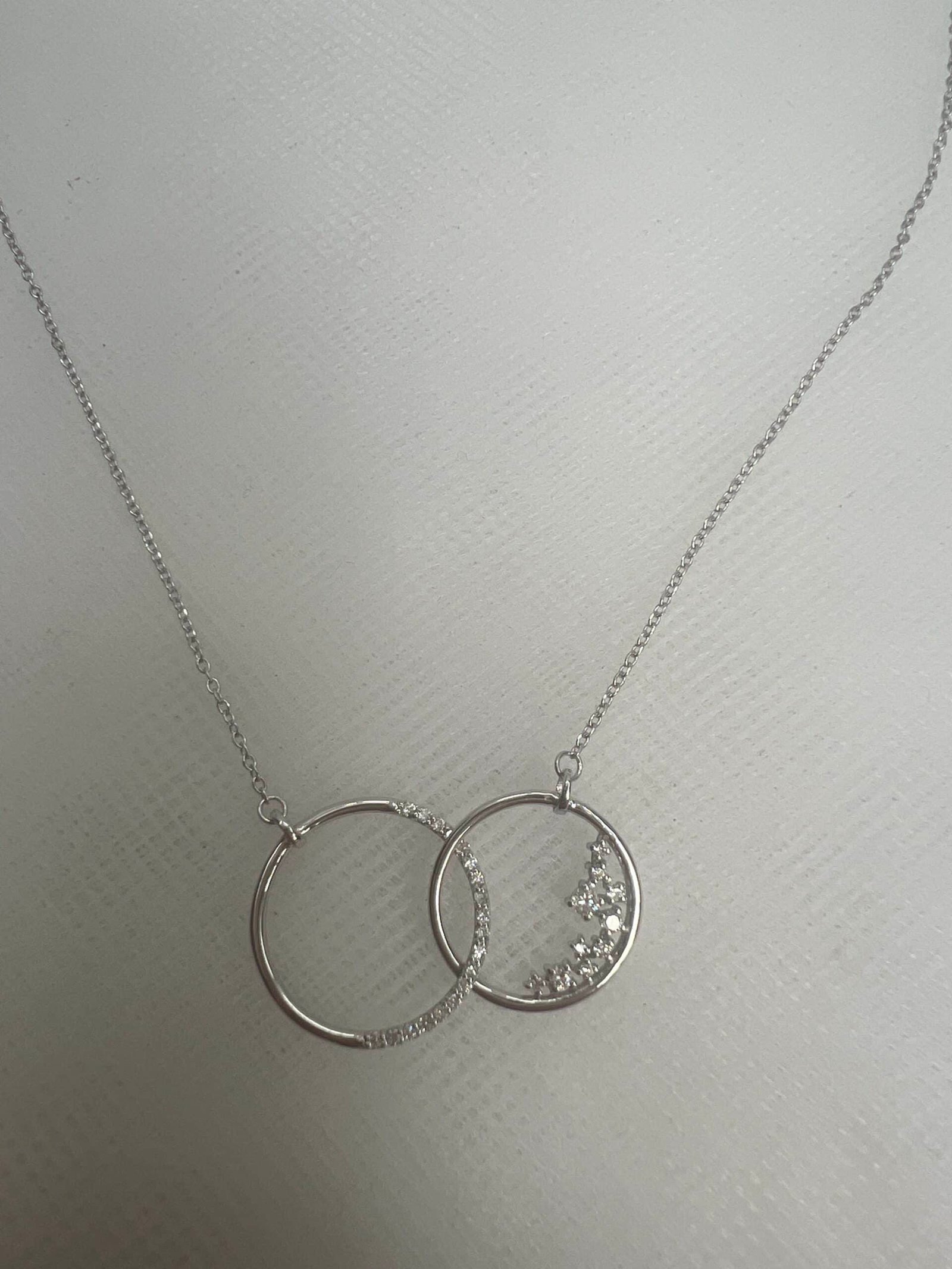 Collar de oro blanco con colgante de  dos circulos entrelazados con brillantes.0.194k.