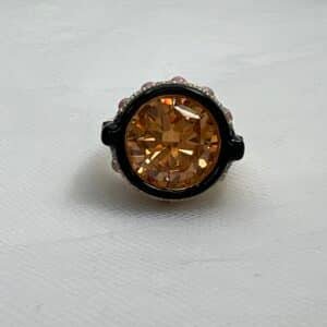 Anillo de plata chapado en oro amarillo con circonita de color ambar bordeada de esmalte negro y piedras naturales y circonitas blancas.