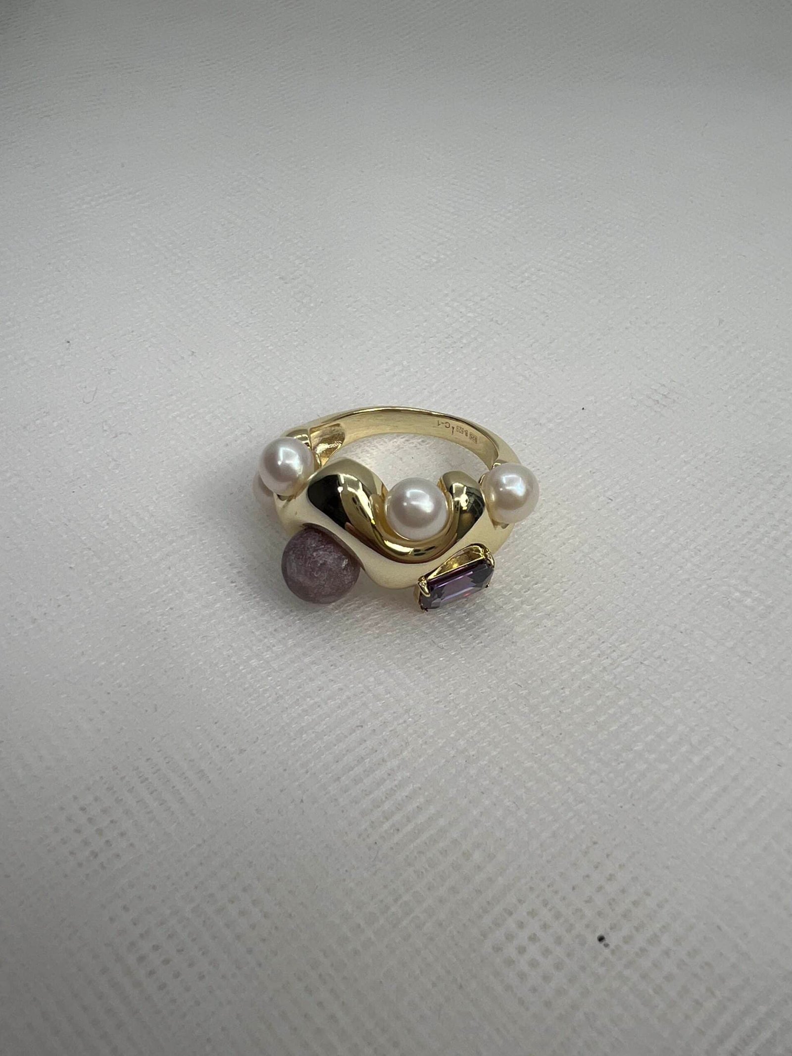 Anillo chapado en oro amarillo con circonita de color morado y perlas y piedra naturales.