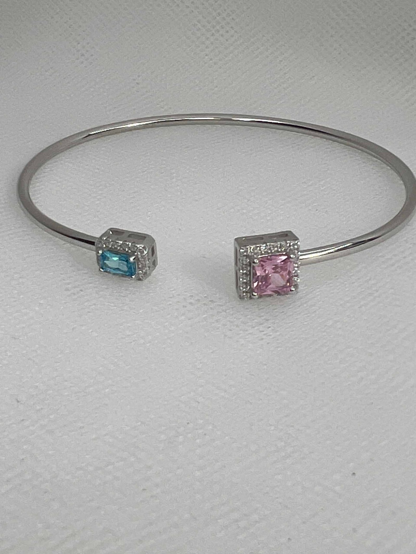 Esclava de plata rodiada en oro blanco abierta en el centro con circonitas azul,rosa y blancas.