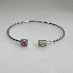 Esclava de plata rodiada en oro blanco abierta en el centro con circonitas de color rosa, verde y blancas.