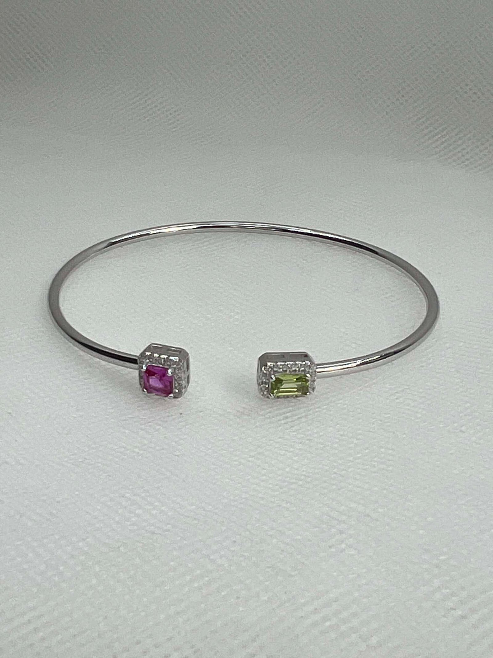 Esclava de plata rodiada en oro blanco abierta en el centro con circonitas de color rosa, verde y blancas.