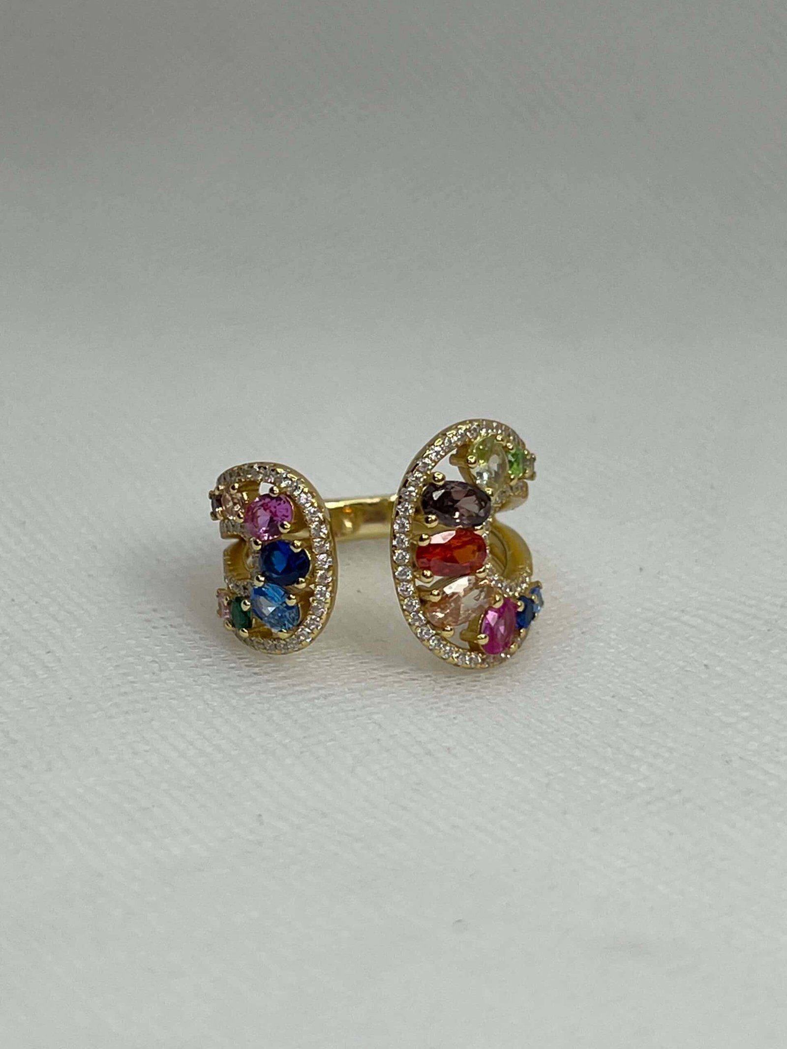 Anillo de plata chapado en oro amarillo abierto por el centro con circonitas de colores y blancas.