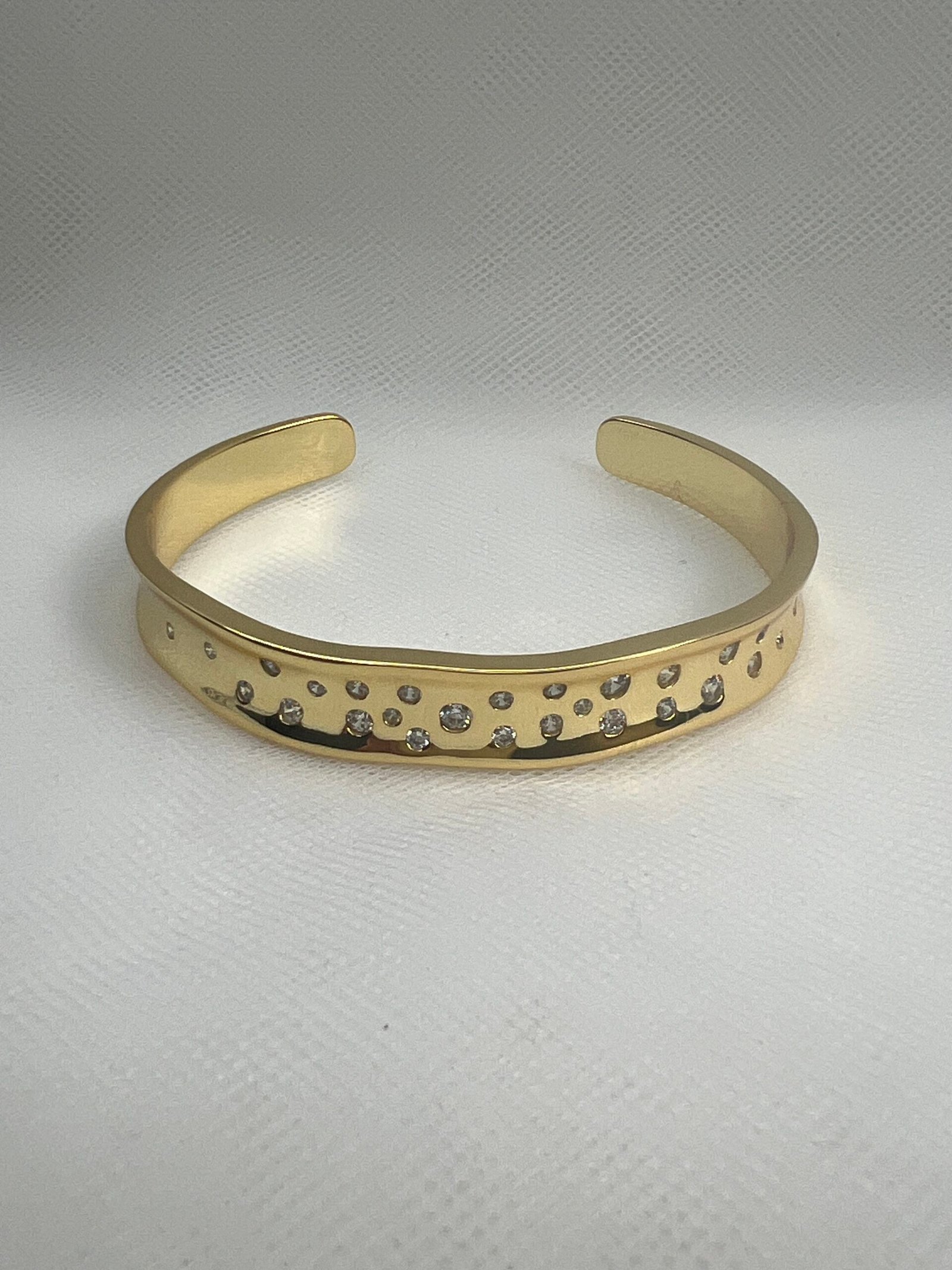 Esclava abierta de plata chapada en oro amarillo con circonitas engastadas de distintos tamaños.