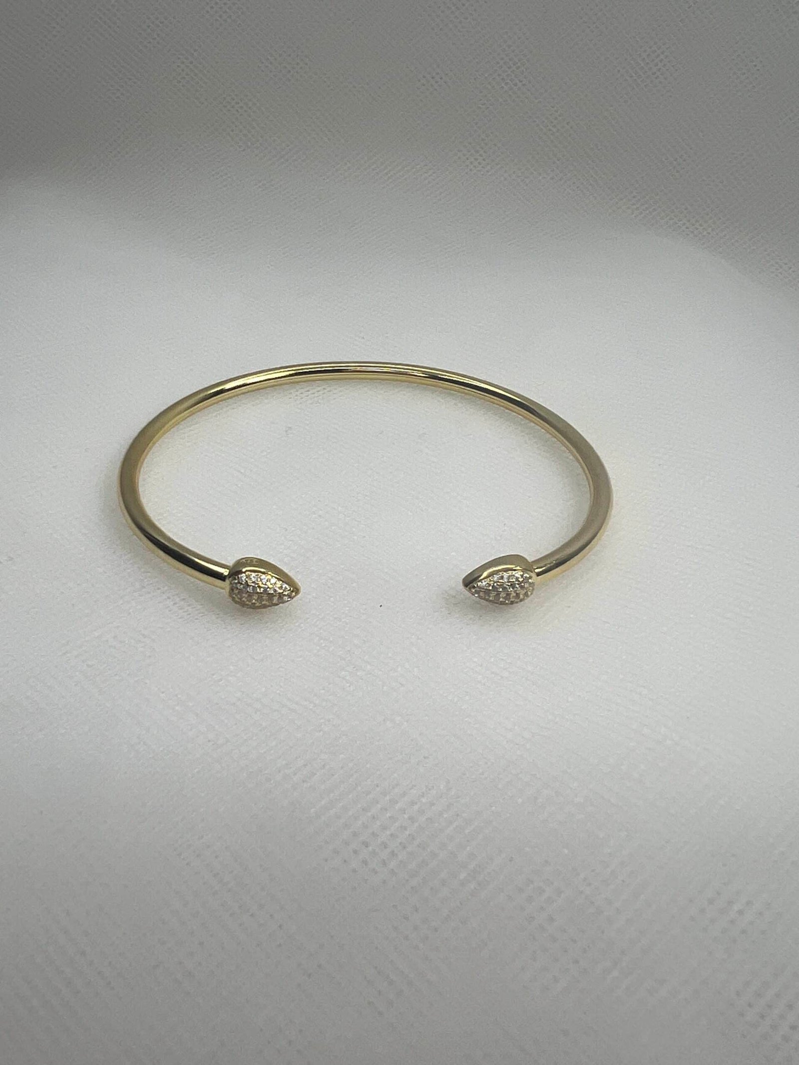 Esclava de plata chapada en oro amarillo abierta en el centro con terminacion en forma de gota con circonitas.