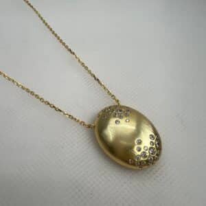 Collar de plata chapada en oro amarillo cadena con colgante ovalado matizado con circonitas engastadas de distinto tamaño.