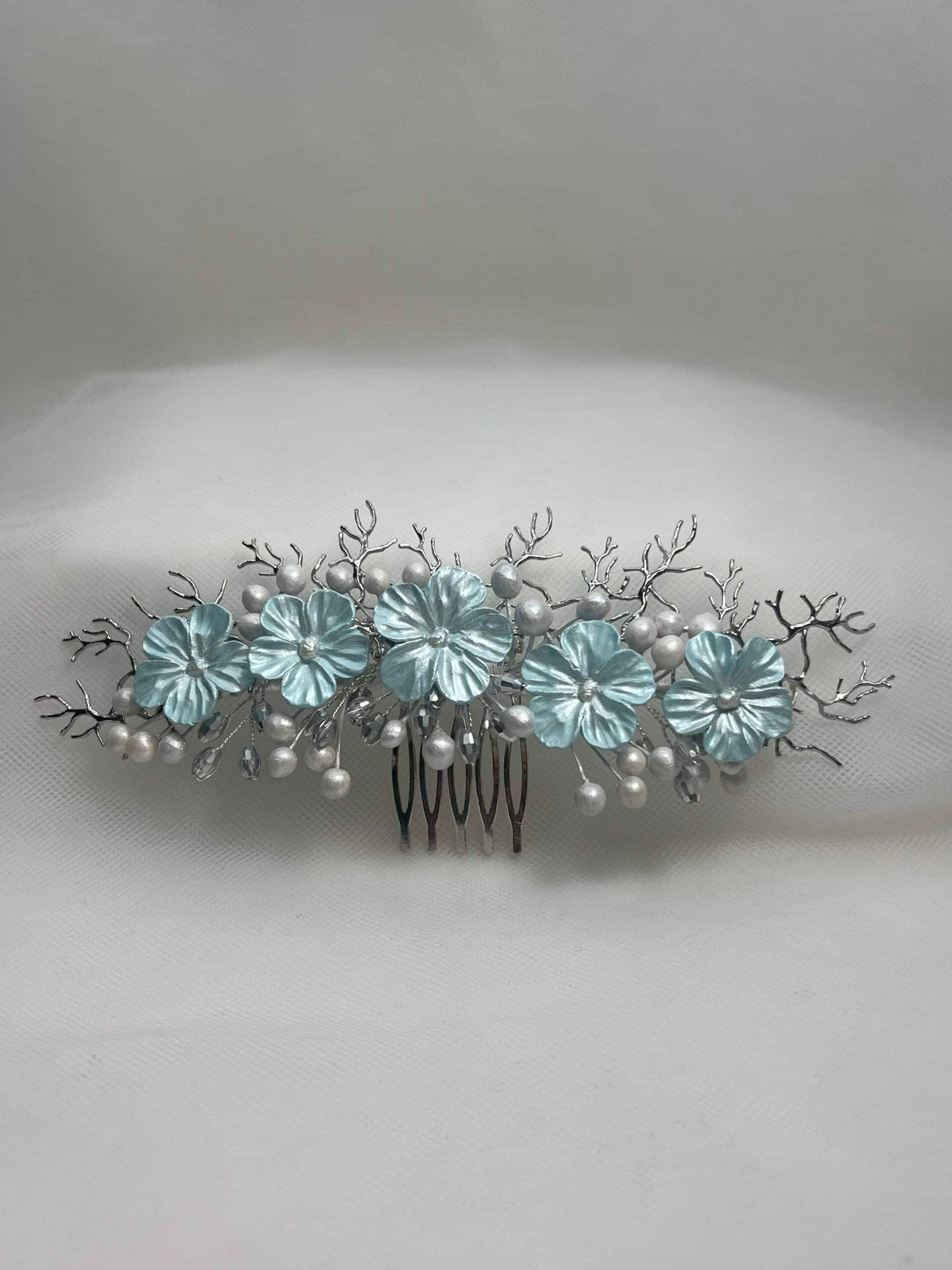 Tocado de flores de porcelana y ramitas de metal plateado.